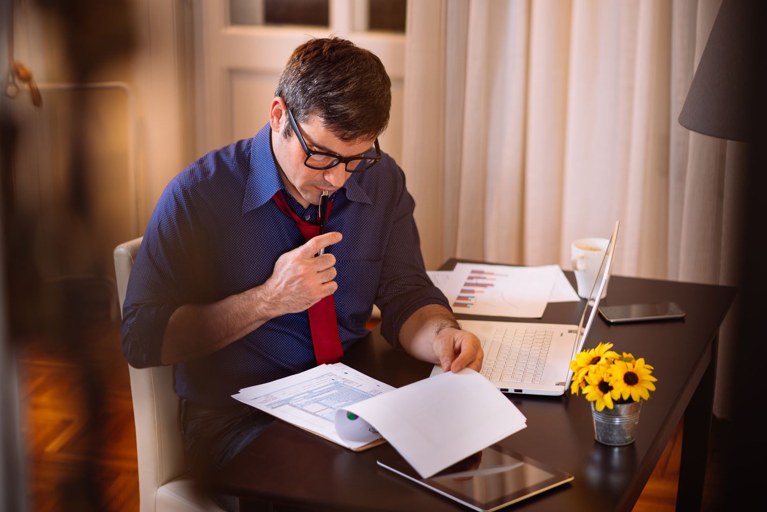 Man sitting in at a table at home studying documents.