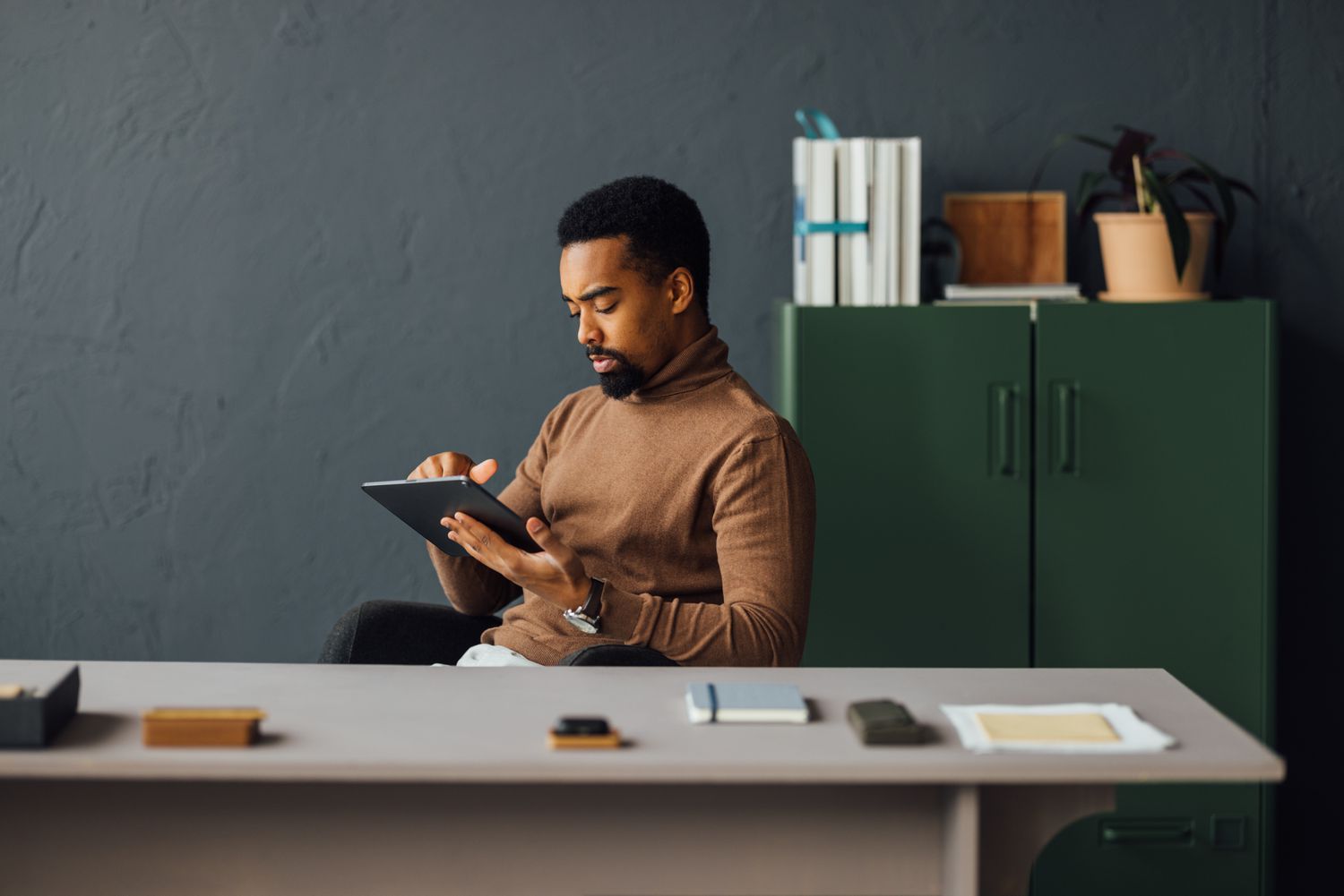 A man sits at a desk using a tablet to research the differences between 504 loans and 7(a) loans from the SBA.