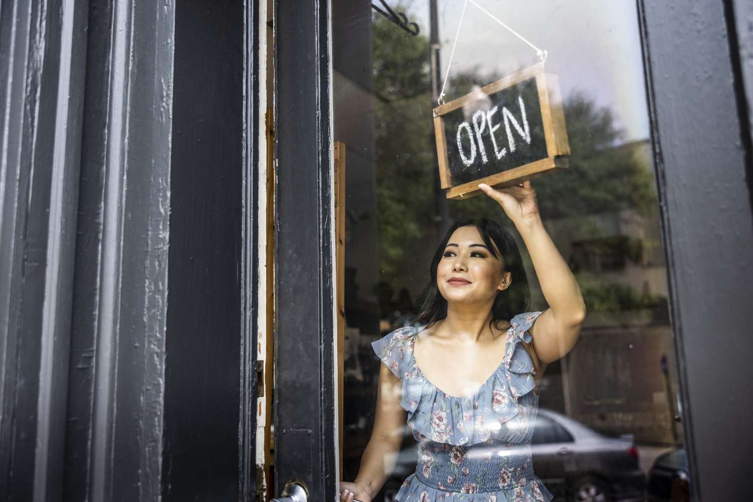 Small business owner turning open sign in her store window