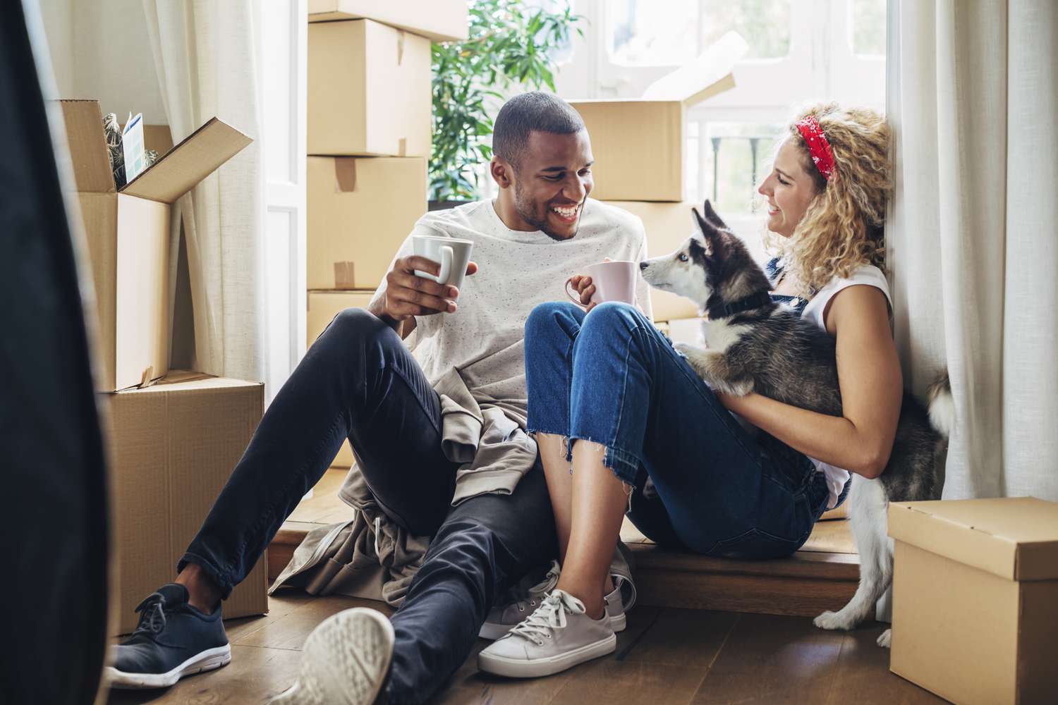 A happy couple sits among unpacked boxes in their new home. 