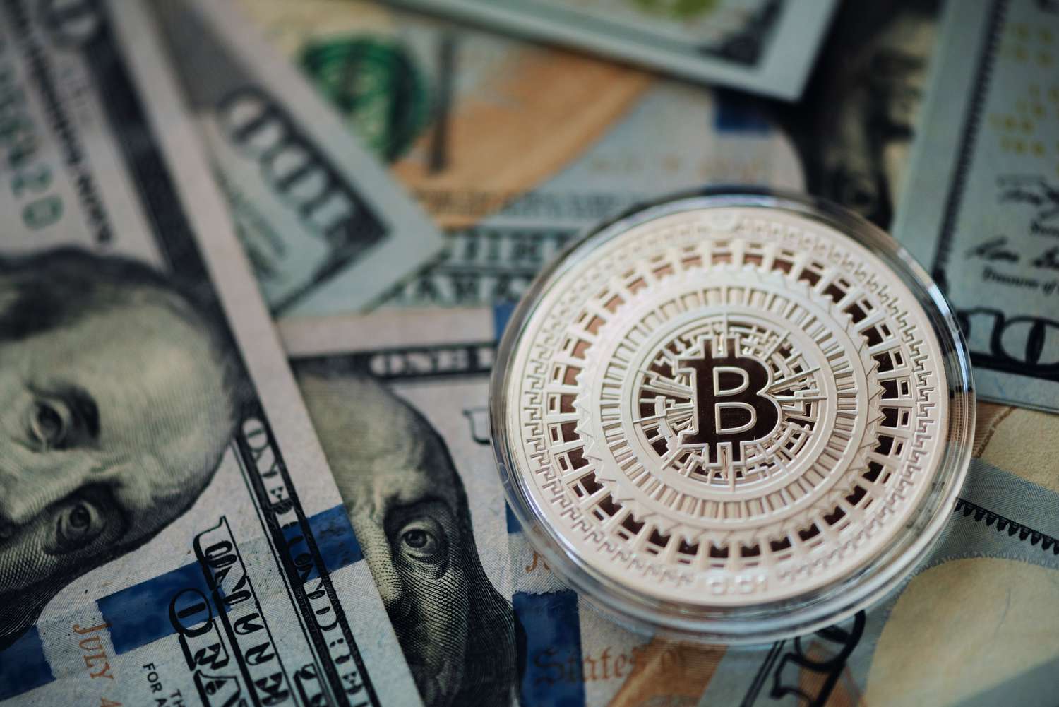 A Bitcoin token and U.S. banknotes.