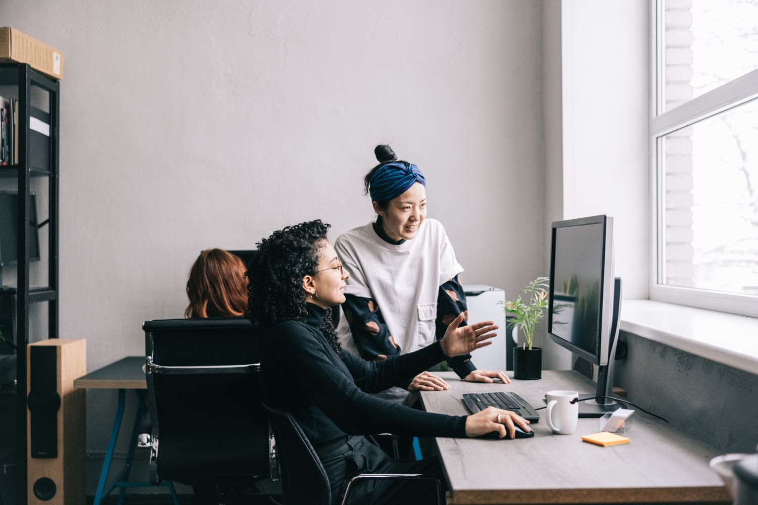Young creators conversing and looking at a computer monitor.