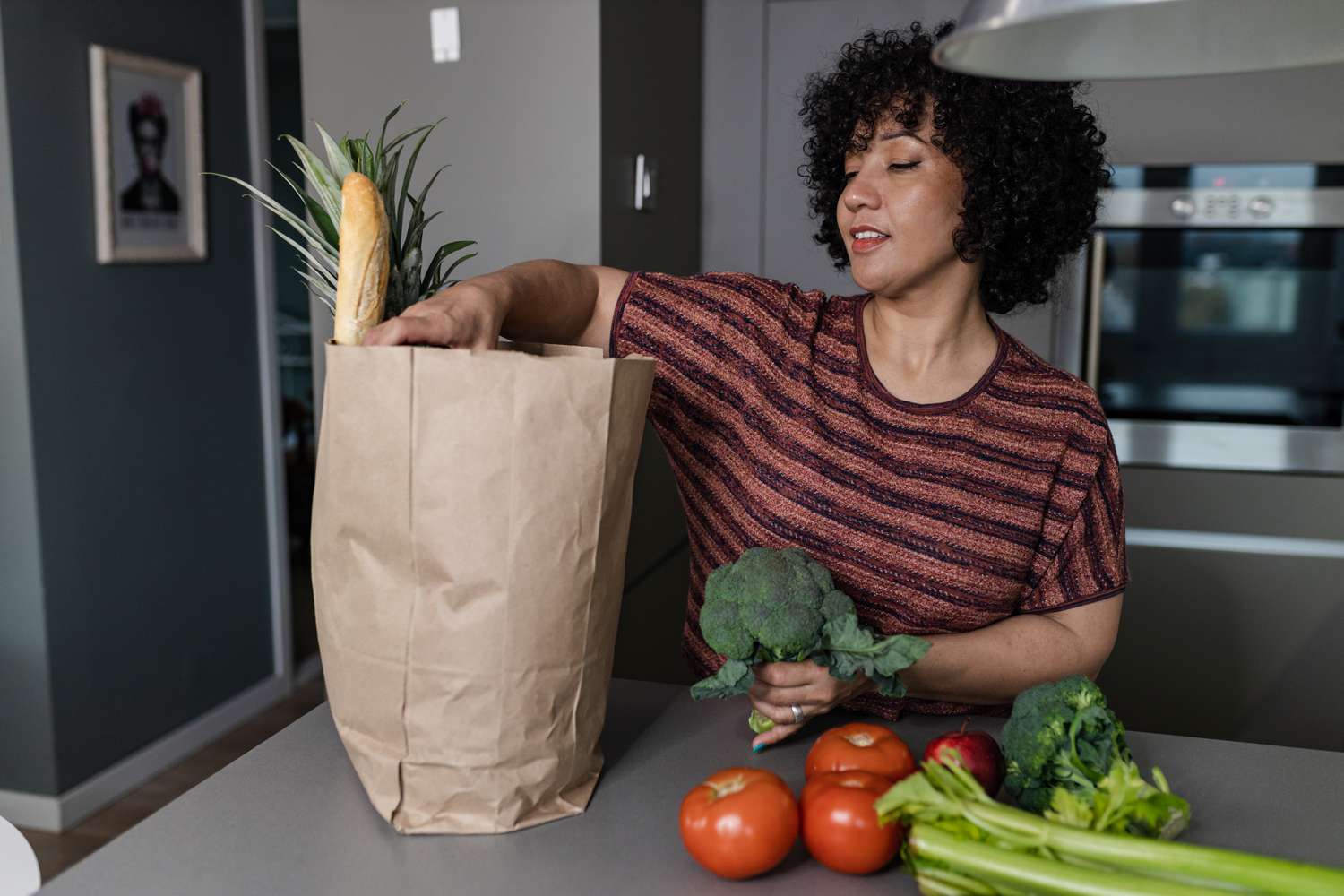 Woman unpacking a bag of groceries in a kitchen