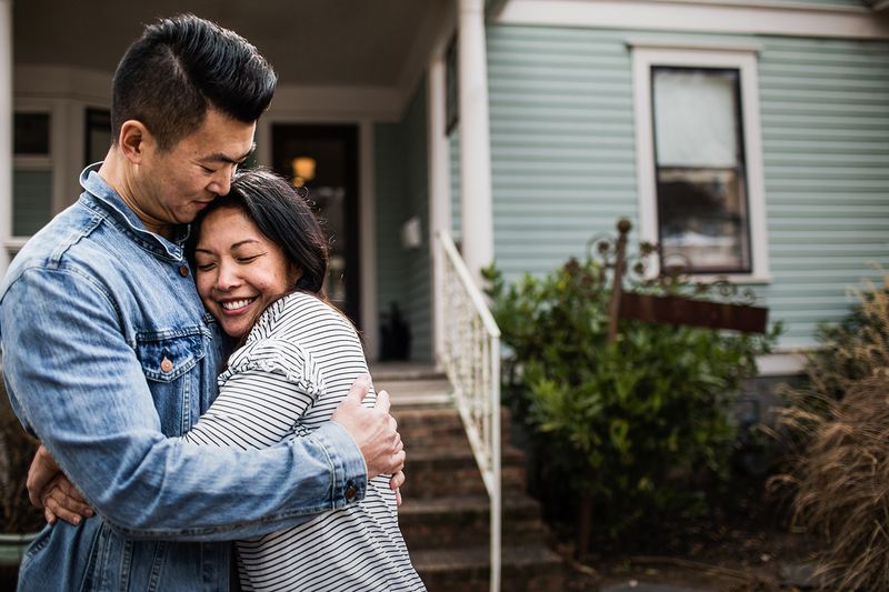 A young couple in front of a home