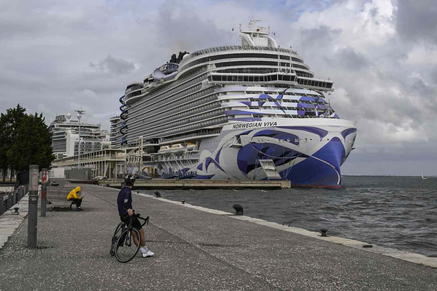 A biker looks at a Norwegian cruise ship