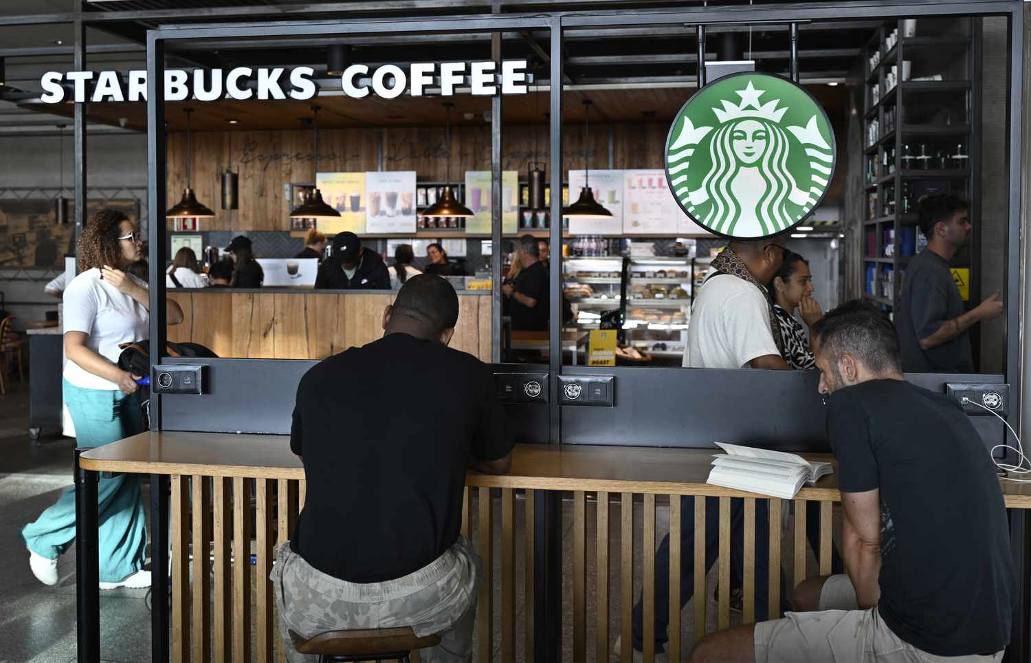 Patrons sit at Starbucks Coffee in Terminal 1 Arrivals Hall at Humberto Delgado International Airport on August 2, 2024, in Lisbon, Portugal