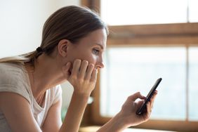 Young woman at home looking seriously at something on her smartphone