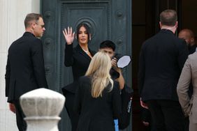Kim Kardashian (center) waves as she arrives at the Assize Court for the trial during which she will testify over the 2016 robbery that saw her relieved of millions of dollars' worth of jewelry at gunpoint in Paris, on May 13, 2025.