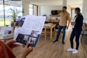 Close-up on a client looking at a house brochure at a real estate showing.