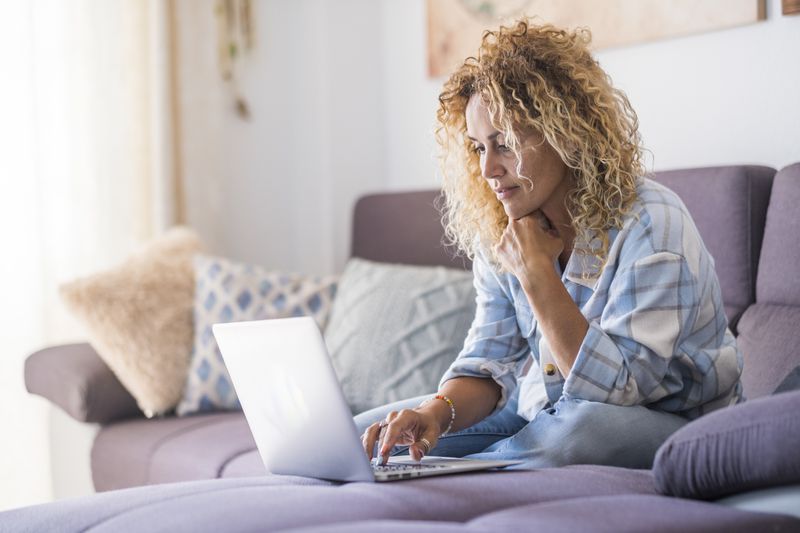 Young woman using phone while sitting on sofa at home