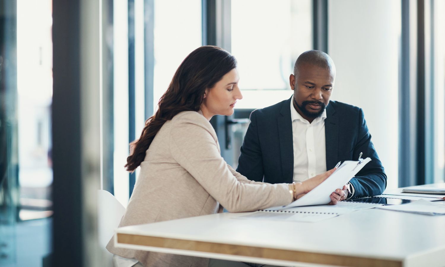 Two people look at paperwork in an office