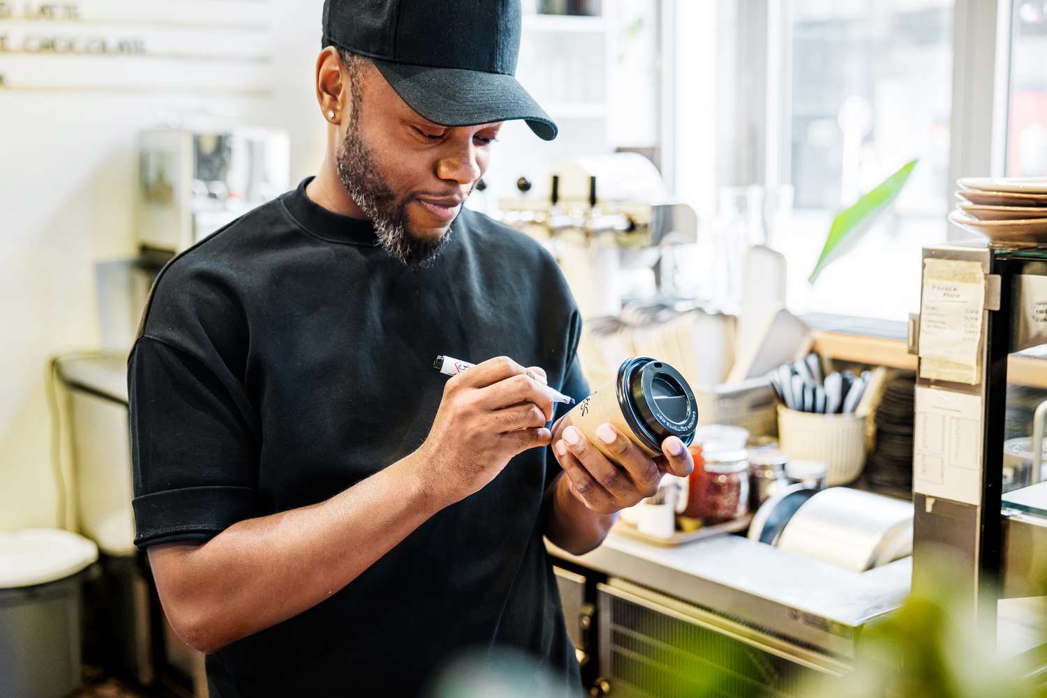 A barista writing a name on a coffee cup