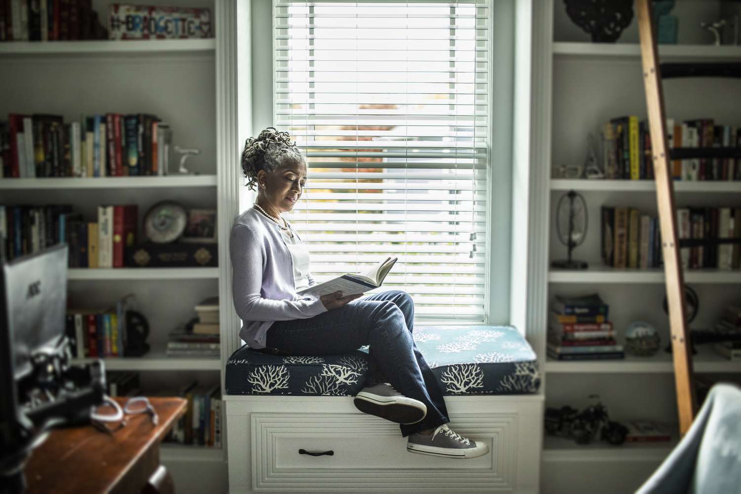 Mature woman on window seat reading a book