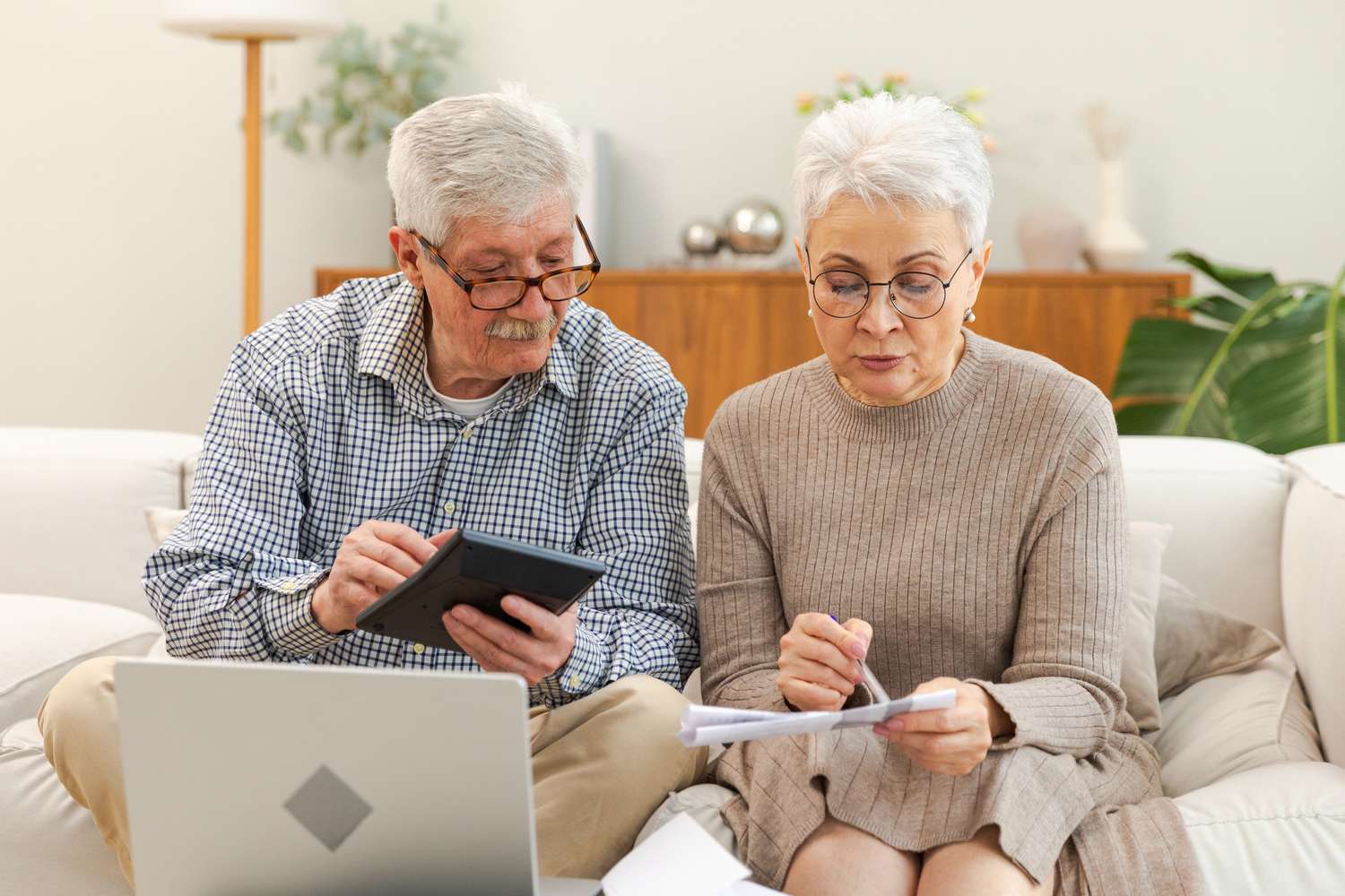 Older couple sitting on their sofa and making mortgage calculations