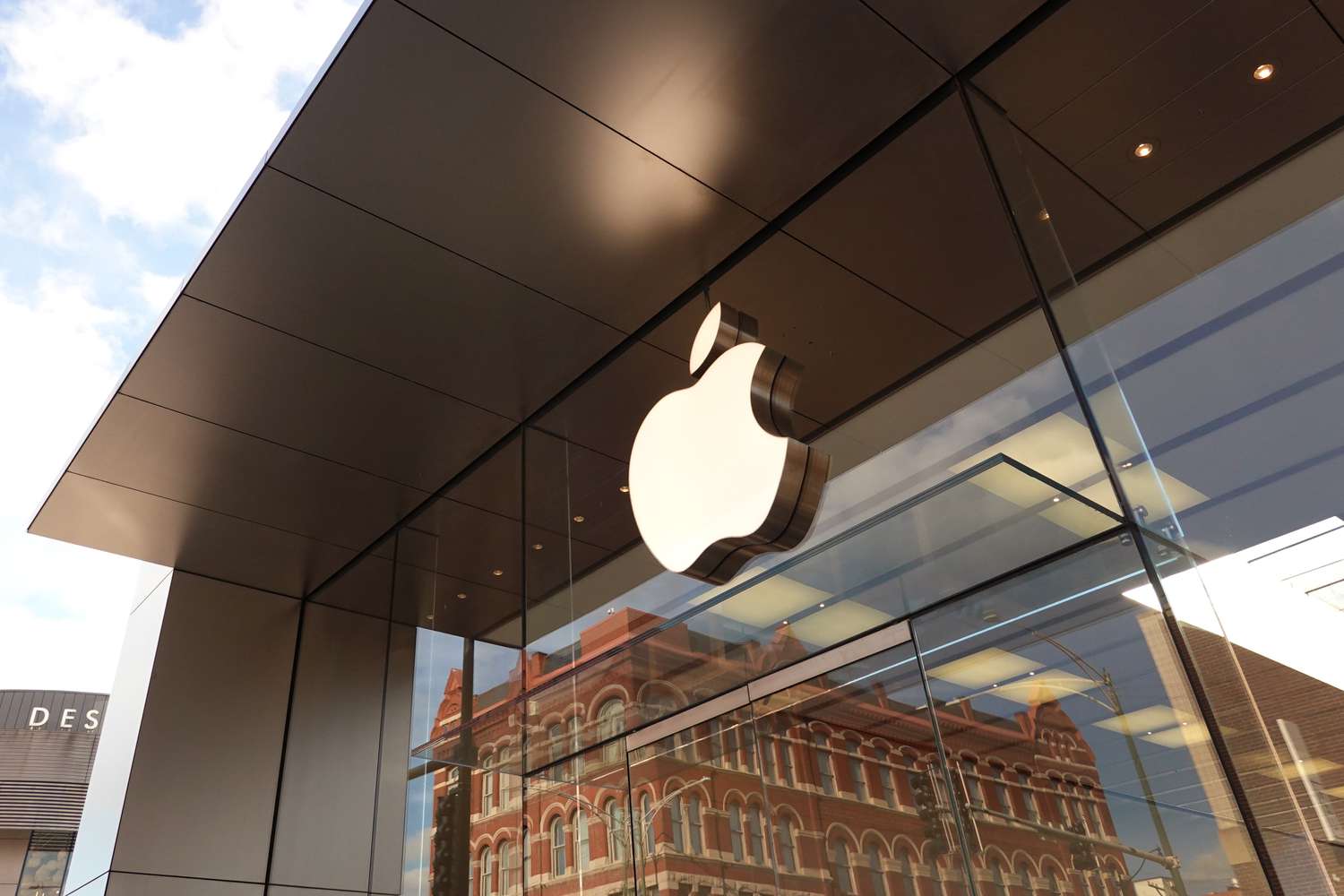 The Apple company logo hangs above an Apple retail store.