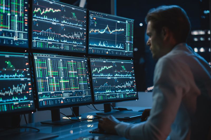 A market maker in front of multiple monitors with market charts