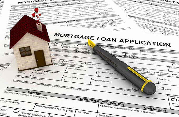 House-shaped paperweight and pen on mortgage loan application form