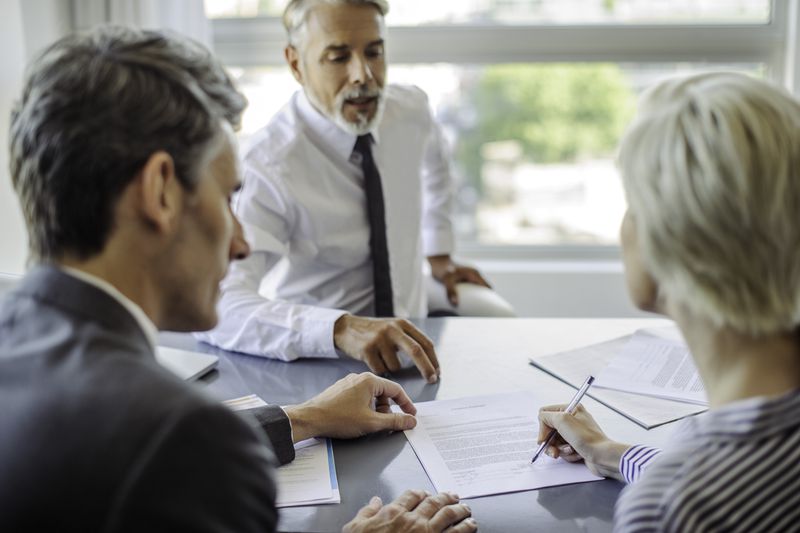 An insurance agent explaing the surrender fee for insurance policy with a couple before they sign the documents.